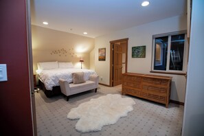Un dormitorio con cama, sofá, cómoda de madera, alfombra y ventana.