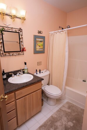 A bathroom with a sink, toilet, and shower curtain.