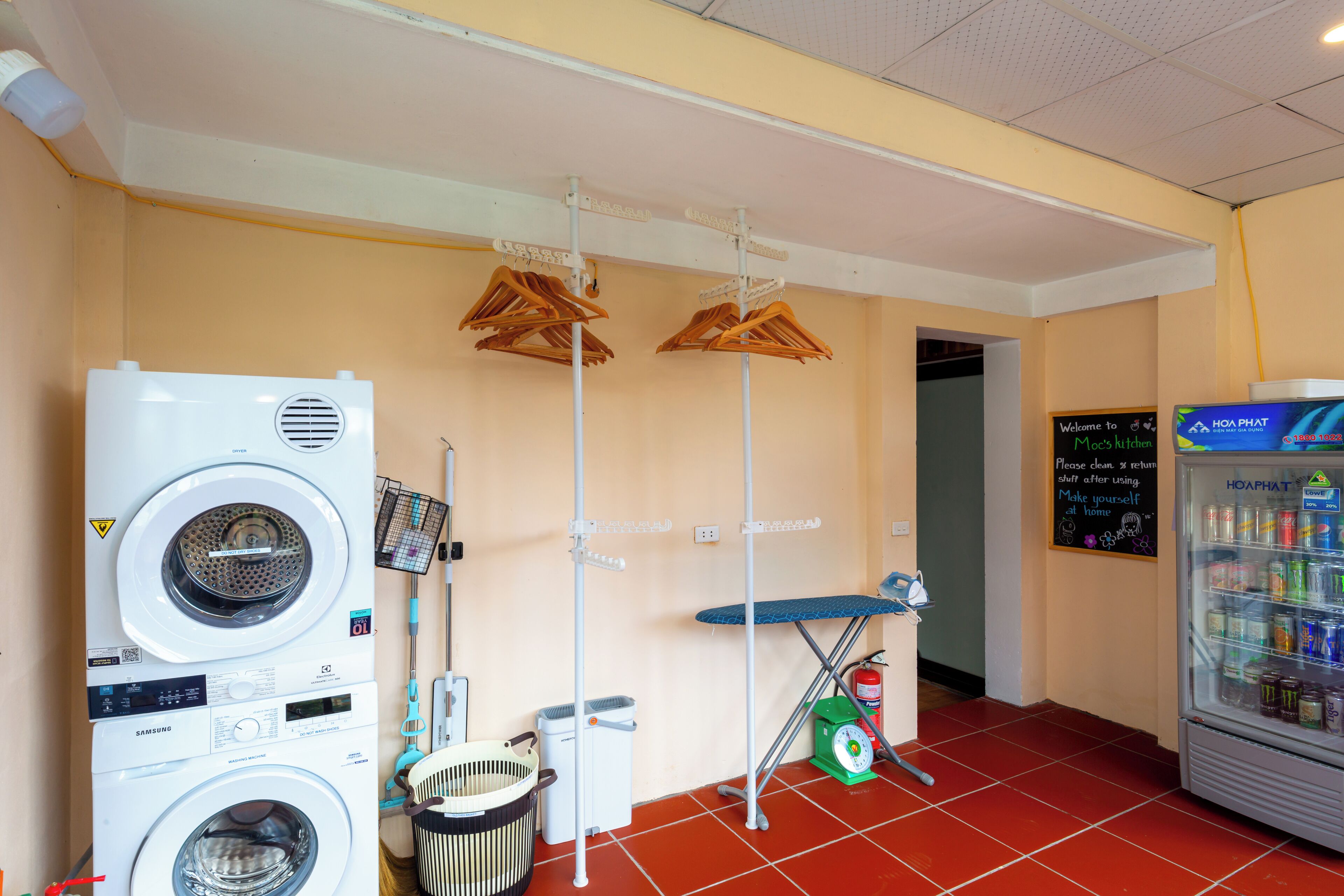 A laundry facility with two washers and dryers, a drying rack, a scale, and a beverage dispenser.
