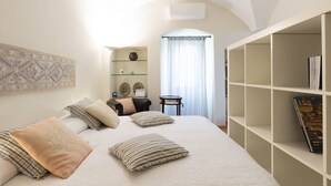 A bedroom with a large bed, a bookshelf, a small table with a vase, and a decorative wall piece. - il Rifugio by Interhome (Bordighera)