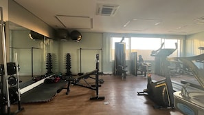 A gym with various exercise equipment, including dumbbells, a bench, and a treadmill.