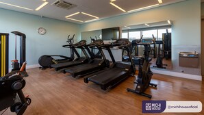 Une salle de sport équipée de tapis de course, de vélos elliptiques et d’un banc de musculation.