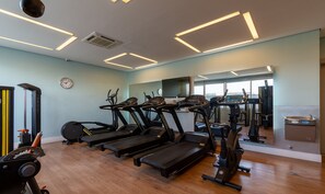 Une salle de sport équipée de tapis de course, de vélos elliptiques et d’un banc de musculation.