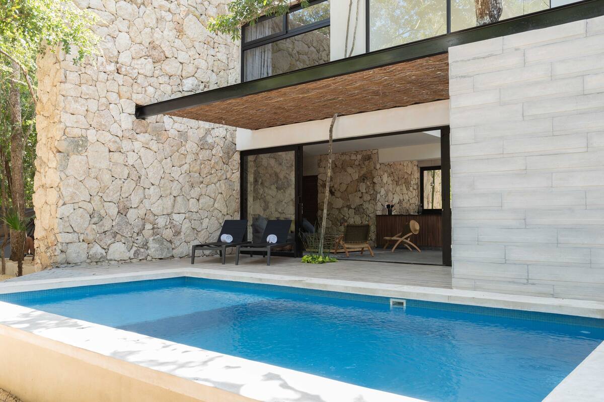 A modern outdoor pool area with stone walls and a wooden deck.
