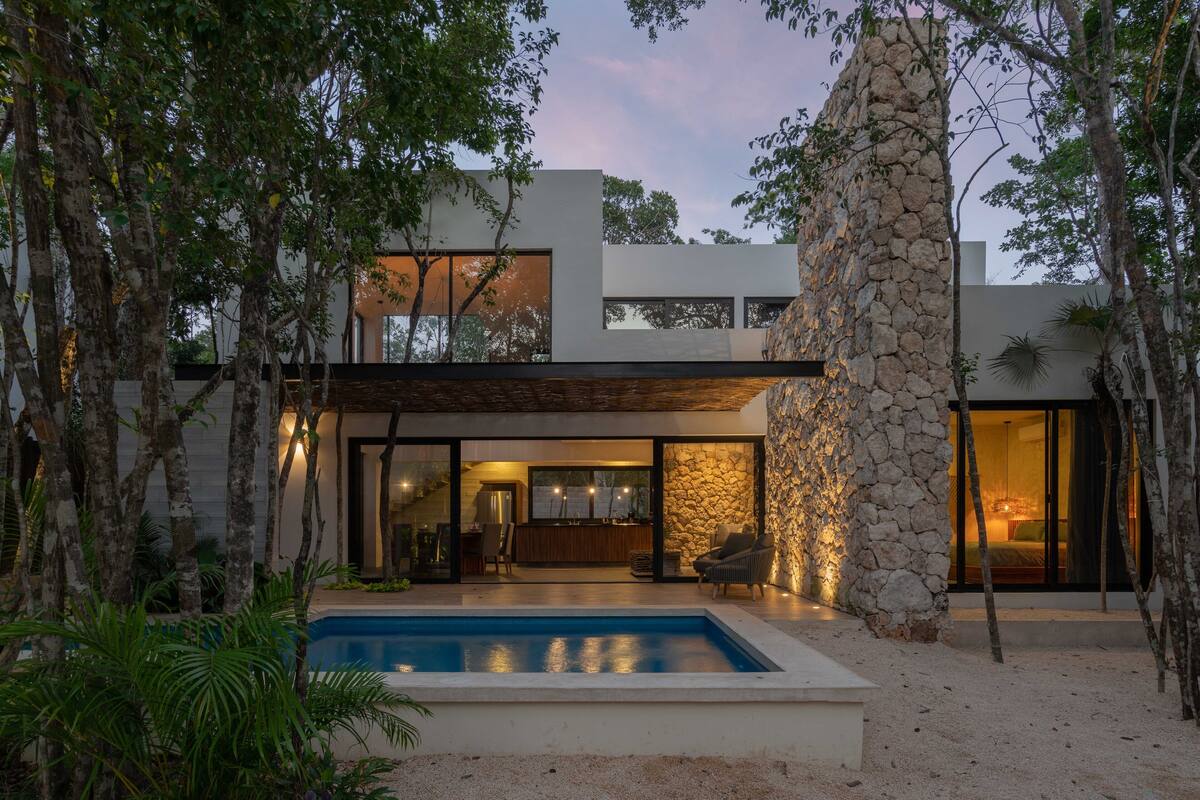 A modern house with a swimming pool, stone walls, and a patio area.