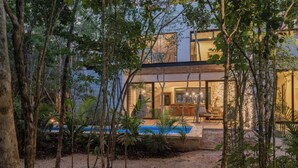 A modern house with a swimming pool, surrounded by trees and plants. - Twelve O’Clock Luxury Villas (Tulum)