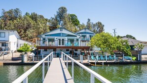 A waterfront property with a dock leading to a house with a covered patio area. - Smiling Otter Retreat! Large Lakefront Luxury House.Pool.Spa.Sauna.Games..Pets (Clearlake)