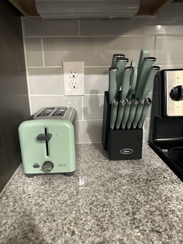 A kitchen with a light green toaster, a knife block, and a microwave.
