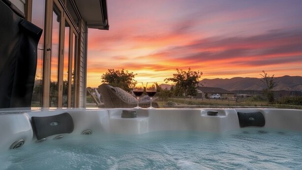 Ein Whirlpool mit Sonnenuntergangsblick, ein Haus im Hintergrund und Berge in der Ferne.