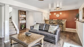 A living room with a gray sofa, a wooden coffee table, and a staircase leading to another level. - Mid-Farmers Park (Colorado Springs)