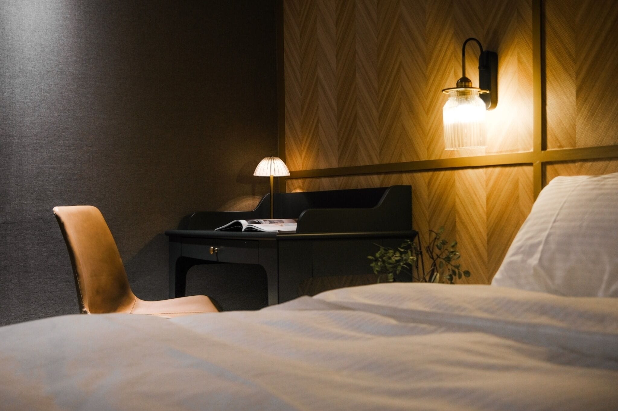 Une chambre d’hôtel avec un lit, un bureau doté d’une lampe et une chaise.