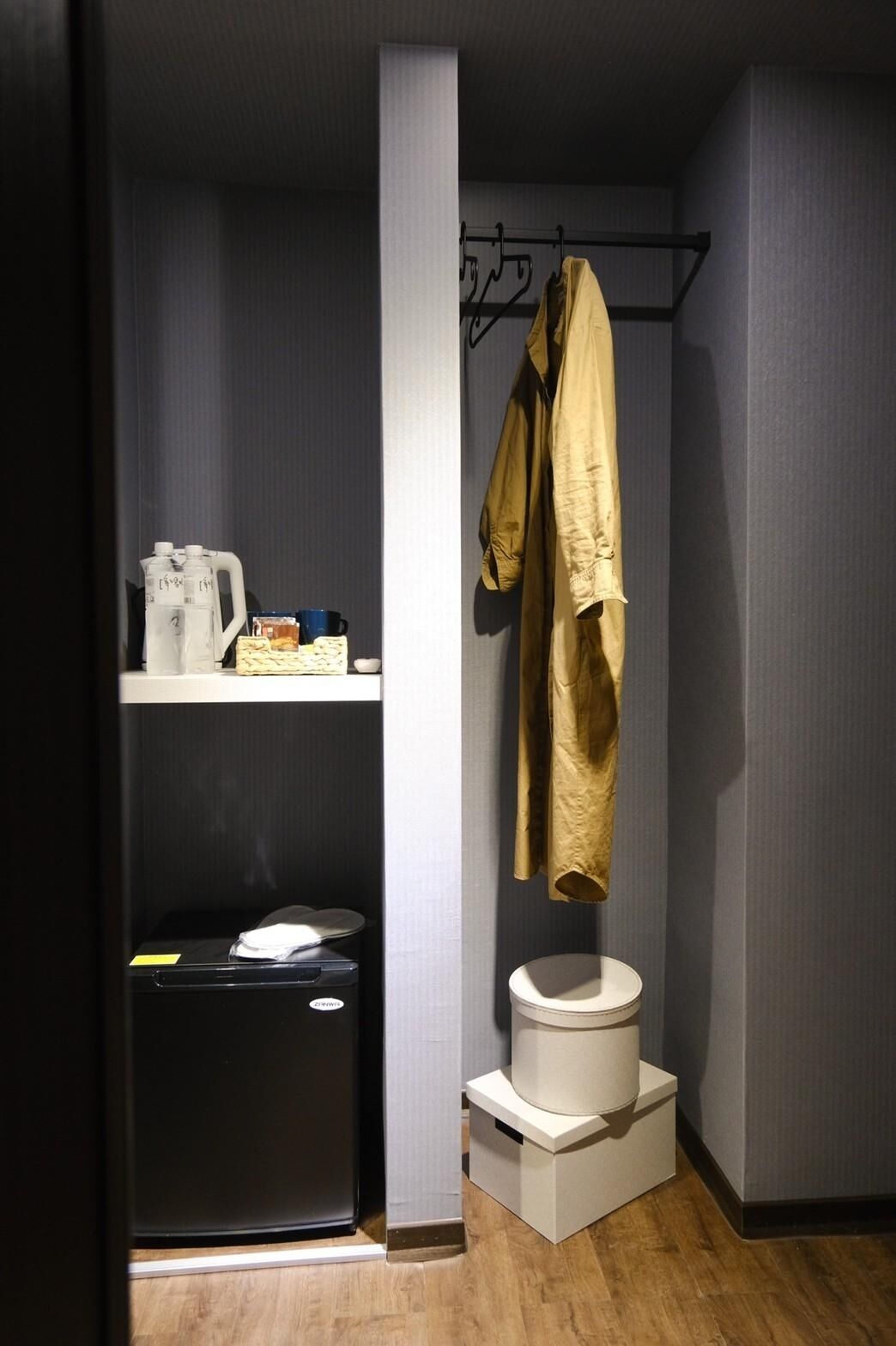A compact bathroom with a toilet, a shelf with toiletries, and a hanging towel rack.