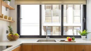 A modern kitchen with a large window, wooden cabinets, and a fruit bowl on the counter. - Alameda Butterfly Living4malaga (Málaga)