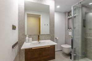 A modern bathroom with a white sink, a large mirror, a wooden vanity, a glass shower enclosure, and a toilet. - Alameda Butterfly Living4malaga (Málaga)