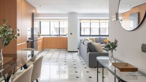 A modern living room with a sofa, a dining table with chairs, a kitchen area, and a large window. - Alameda Butterfly Living4malaga (Málaga)