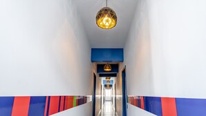 Un pasillo moderno con una lámpara de diseño geométrico, detalles azules y rojos en las paredes y un suelo reflectante.