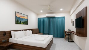 Una habitación de hotel moderna con una cama, un escritorio, una silla, un televisor y un aire acondicionado.
