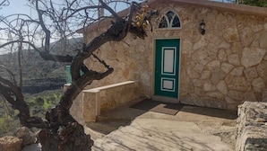 A stone building with a green door, a bench, and a tree in front.