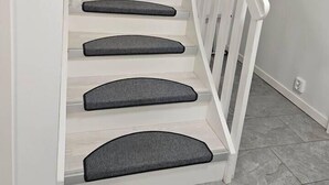 A staircase with white railings and grey carpeted steps.