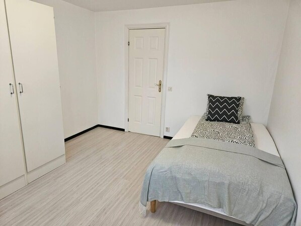 A bedroom with a bed, a wardrobe, and a door. - 3Br House, Sleeps 7 with Balcony-Garden-Bbq-FreeP (Malmo)
