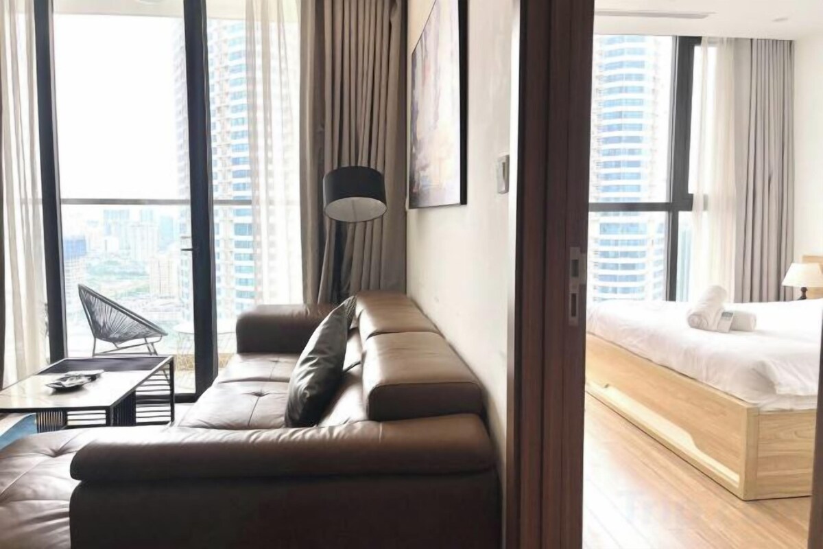 Une chambre d’hôtel moderne avec un canapé, un lit, un bureau et une vue sur la ville.