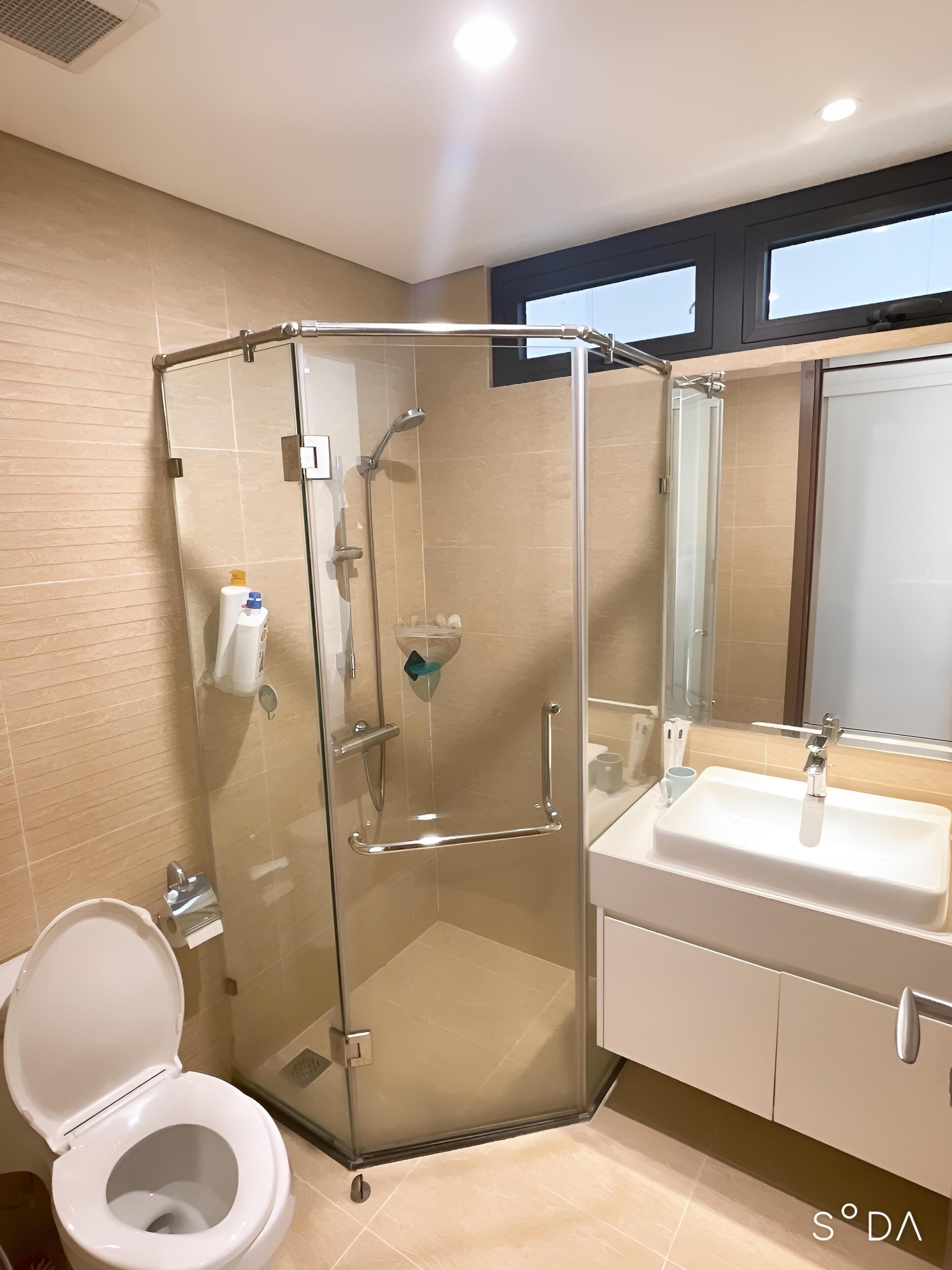 Un baño moderno con ducha de vidrio, un lavamanos blanco y un inodoro.