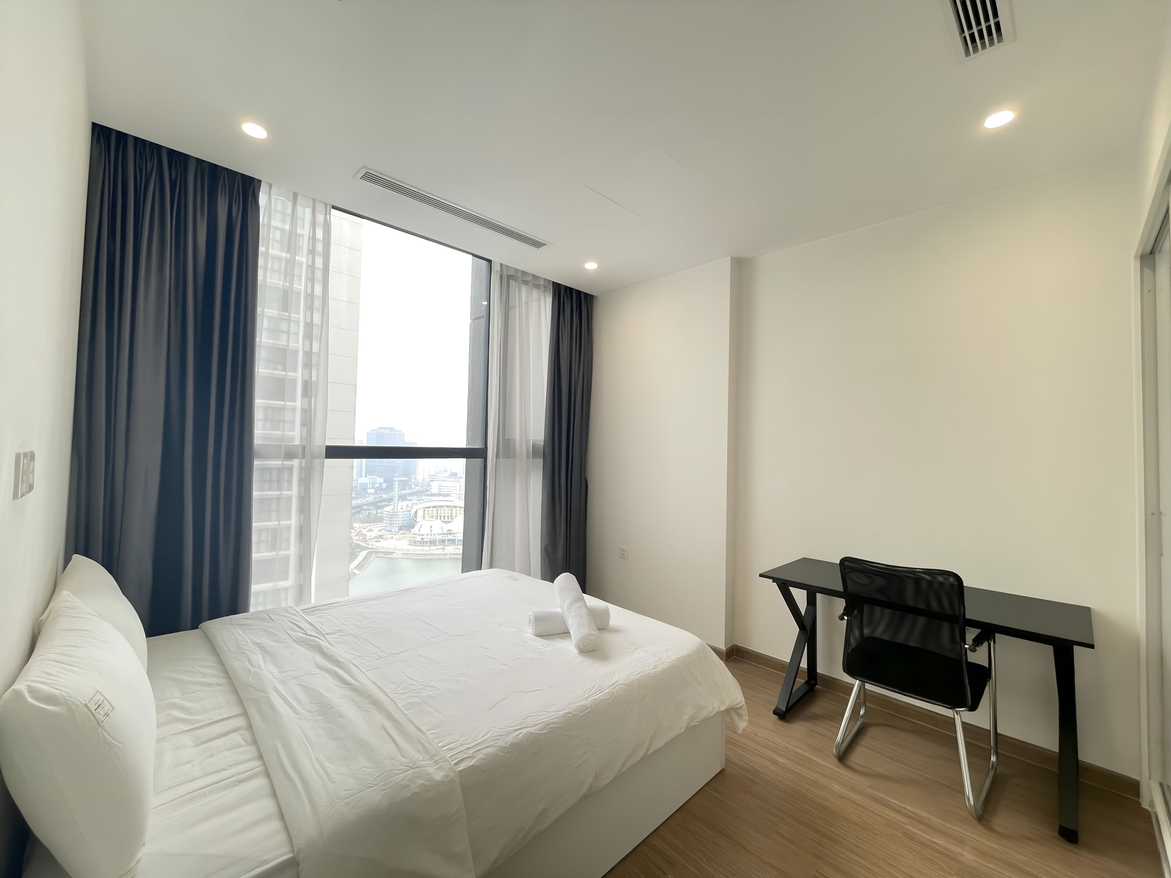 A hotel room with a bed, a desk, and a chair.