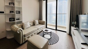 A modern living room with a beige sofa, a round coffee table, and a TV stand.