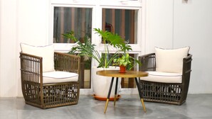 Two wicker chairs with cushions, a small round table, and a potted plant between them. - Bambu Suites (Puerto Princesa)