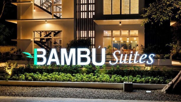 A multi-story building with a prominent 'Bambu Suites' sign, large windows, and a staircase leading to the upper floors. - Bambu Suites (Puerto Princesa)