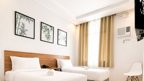 A hotel room with two beds, a desk, a chair, and a TV. - Bambu Suites (Puerto Princesa)