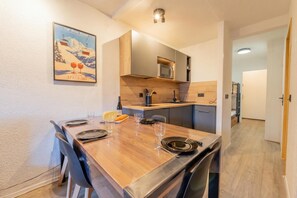 Una cucina moderna con mobili in legno, un tavolo da pranzo per quattro persone e un poster a tema sci.