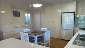 A modern kitchen with white cabinetry, a central island with a sink, and a refrigerator. - Fully Self contained 1bedroom spacious unit adjoining rear of owners home. (Jandakot)