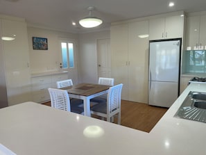 Eine moderne Küche mit weißen Schränken, einer zentralen Kochinsel mit Spüle und einem Kühlschrank.