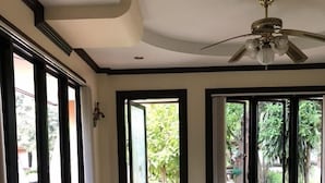 Una habitación amplia con techo alto, ventanas grandes y un ventilador de techo.