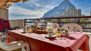 A table set for breakfast with a view of a mountain and buildings.