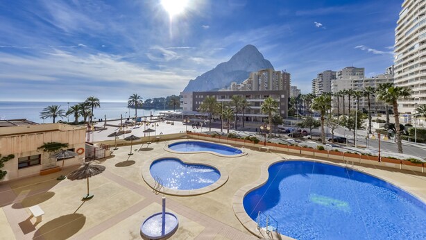 A resort with multiple swimming pools, a beach, and a mountain in the background.