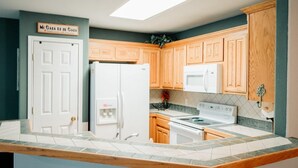 Una cocina con armarios de madera, un refrigerador blanco, una estufa y un letrero sobre la puerta.