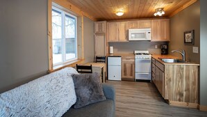 Une cuisine de taille réduite, dotée de meubles en bois, d’un four à micro-ondes, d’une cuisinière et d’un évier.