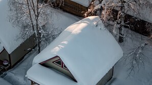 Une maison recouverte de neige, avec un toit en pente et une cheminée bien visible.