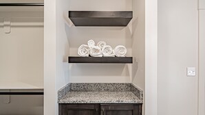 A laundry room with a dark wood cabinet, a granite countertop, and a white wall.