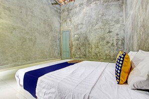 A bedroom with a bed, a blue and white bedspread, a blue door, and a white wall. - Hotel O Agus Kostel SyariahNearWisata Agro Jollong (Pati)