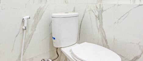 Un baño con inodoro, paredes de mármol y suelo de baldosas.