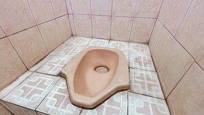 A small, tiled bathroom with a squat toilet. - Hotel O De Lanang Homestay Near Masjid Janapria (Janapria)