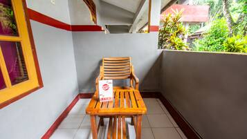 A wooden chair and table on a balcony with a tiled floor, surrounded by walls with a red trim.