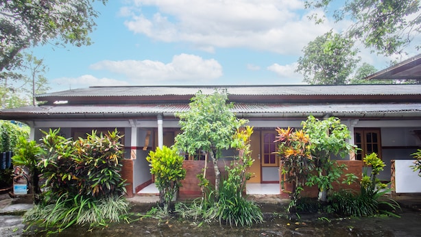 A traditional building with a tiled roof, surrounded by lush greenery and a small water feature in the foreground. - Hotel O De Lanang Homestay Near Masjid Janapria (Janapria)