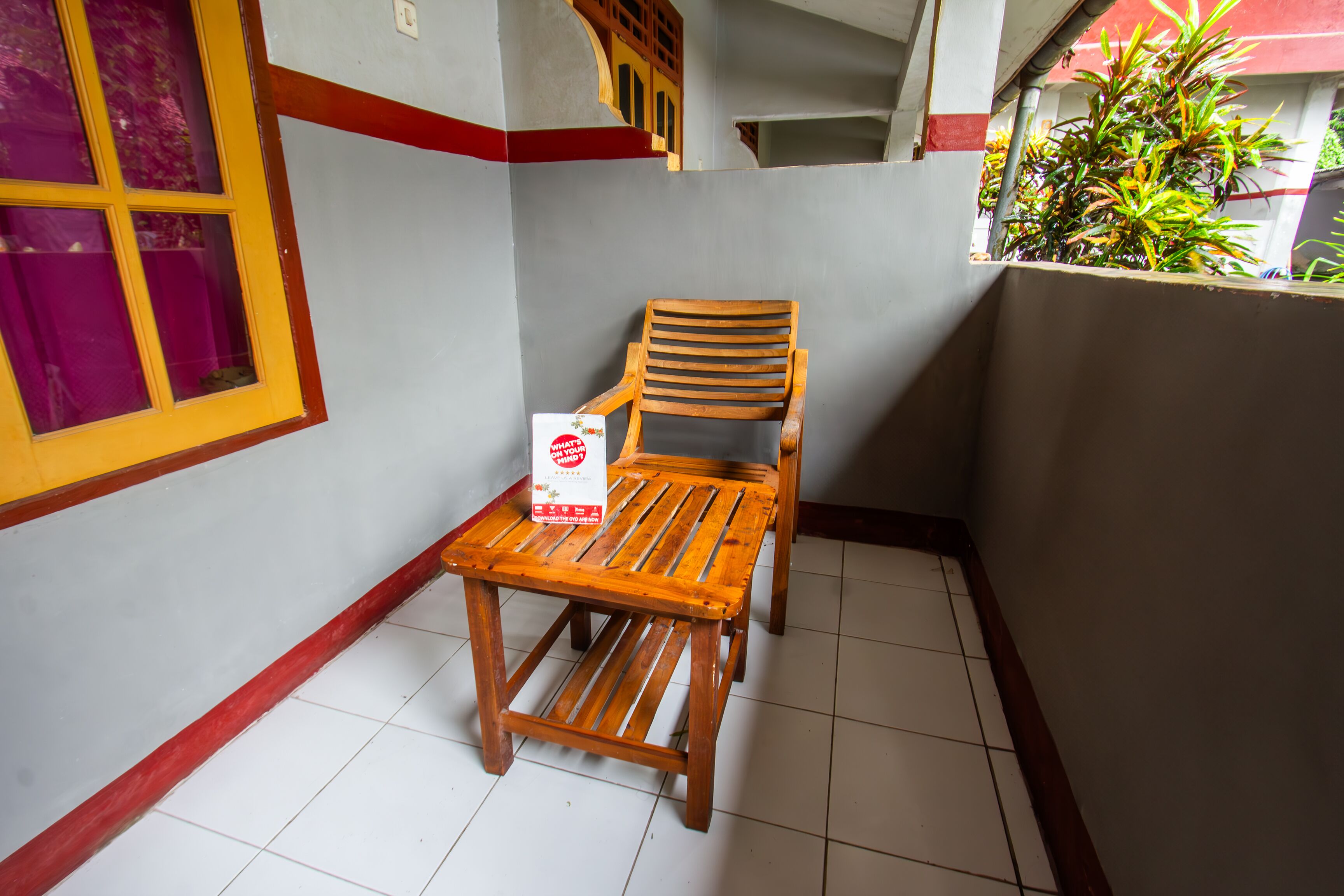 A corner of a room with a wooden chair and a table, a window with purple curtains, and a tiled floor.