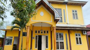 A yellow building with a central entrance, large windows, and a porch with columns.