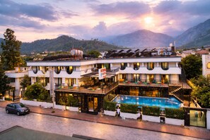 Ein Hotel mit Pool, mehreren Balkonen und Bergblick.