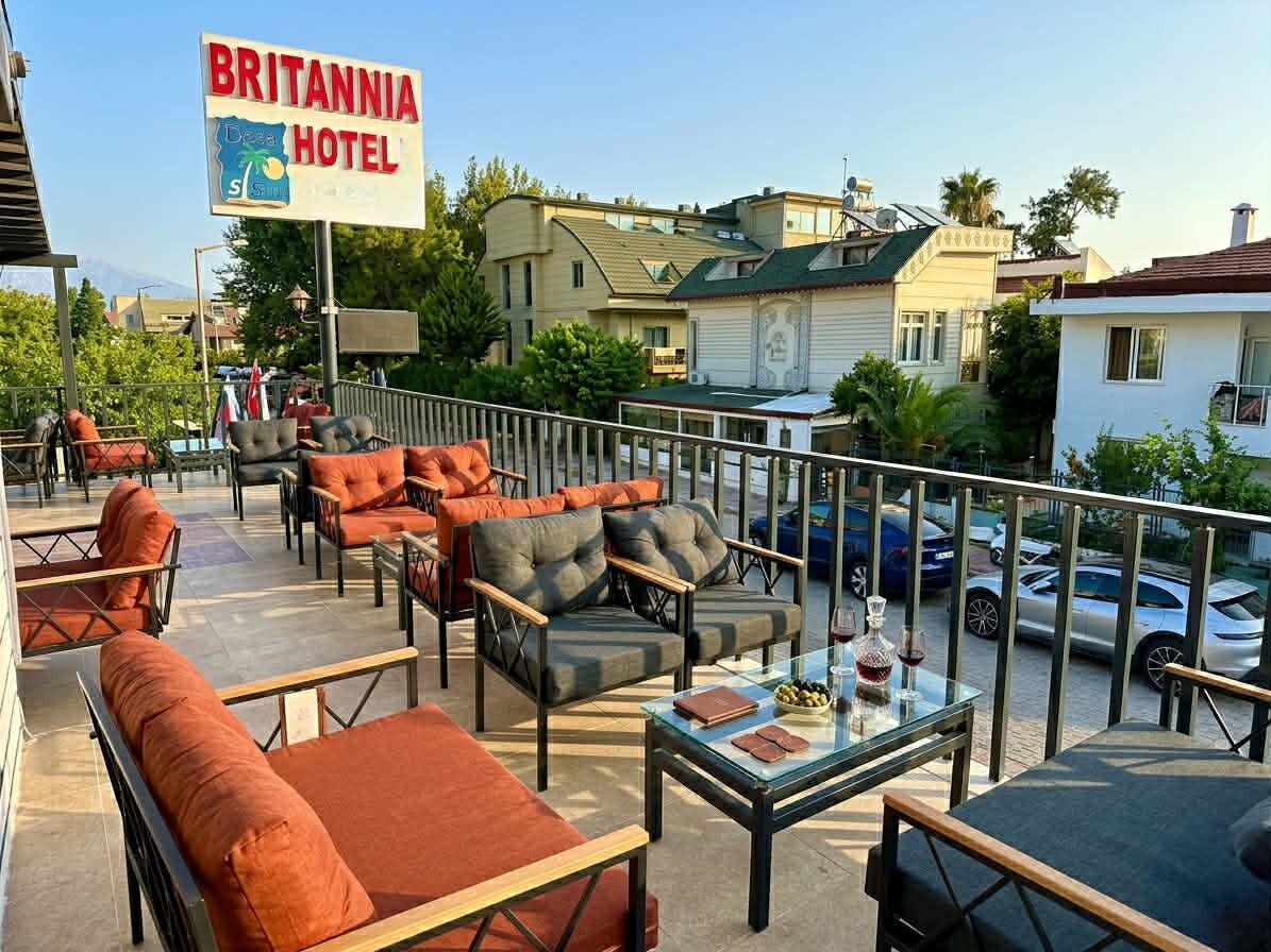 A balcony with outdoor seating, a sign for Britannia Hotel, and a view of the street and buildings.